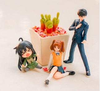 Anime figurines next to a potted plant.