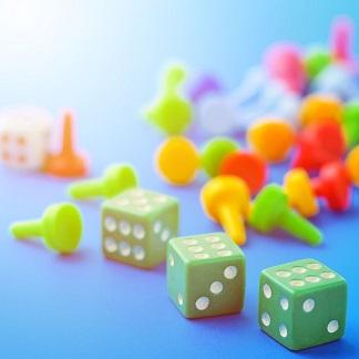 Green dice and multicolor game pieces on a blue background.