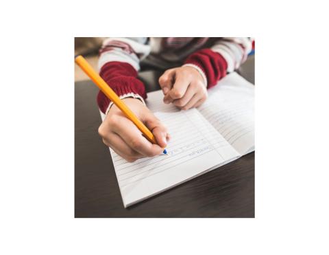 Youth using a pencil to write in a notebook.