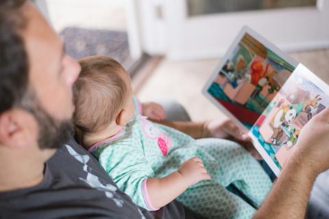 Parent reading a book with baby.