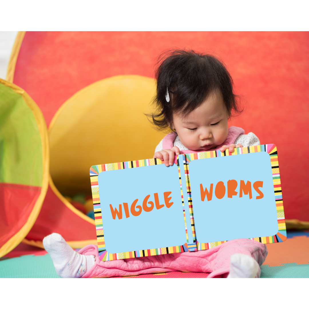 Image of a young toddler holding an open book with the words Wiggle Worms on the open pages.